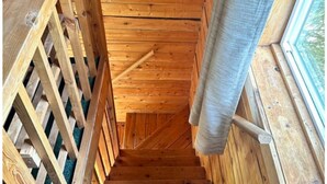 A wooden staircase with a wooden railing on the left and a window on the right. - McNeil River Cabin, Homer Floatplane Lodge (Homer)