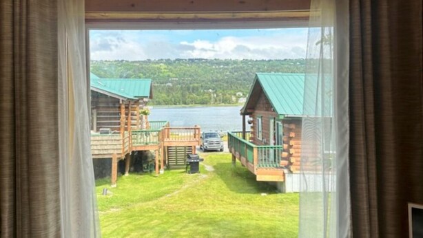 A view from a window of a cabin with a deck and a car parked outside. - McNeil River Cabin, Homer Floatplane Lodge (Homer)