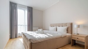 A modern bedroom with a large bed, a bedside table, and a lamp.