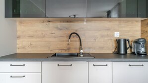 A modern kitchen with a wooden backsplash, a black faucet, and a Bosch coffee maker.