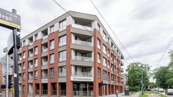 Un immeuble à plusieurs étages doté d’une architecture moderne, avec des balcons et une enseigne indiquant « BIURO SPRZEDAZY ».