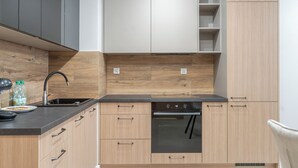 Une cuisine moderne avec des meubles en bois, un plan de travail noir, un évier et un four encastré.