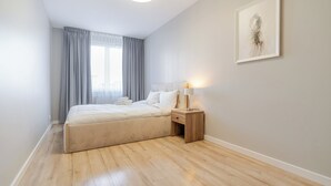 Une chambre à coucher moderne avec un lit, une table de chevet et une œuvre d’art encadrée accrochée au mur.