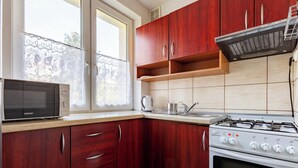 Une cuisine avec des meubles en bois, une cuisinière, un four à micro-ondes et une fenêtre donnant sur les arbres.