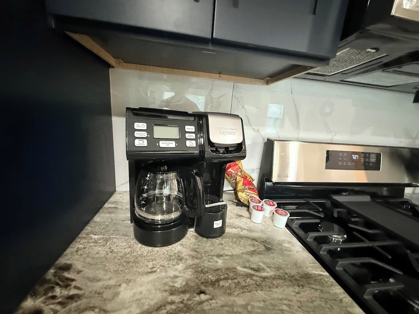 A kitchen with a coffee maker, a stove, and a bag of coffee pods.