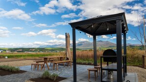 An outdoor patio with a barbecue grill, picnic tables, and a pergola. - Yugen Retreats Furano (Kamifurano)