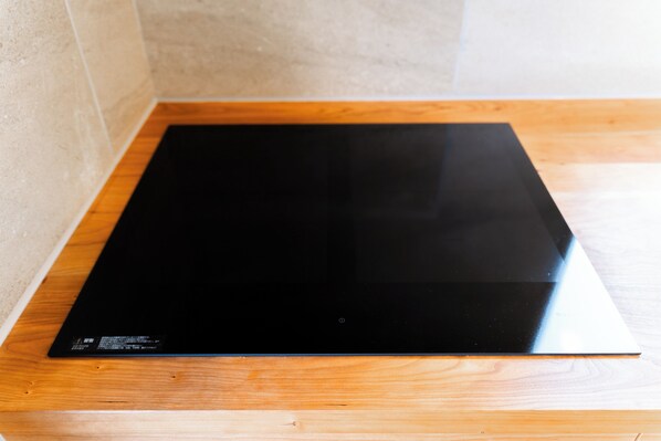 A black induction cooktop on a wooden countertop.