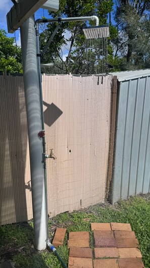 A metal fence, a water spigot, and a brick pathway.