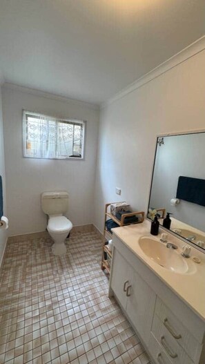 Une salle de bain avec des toilettes, un lavabo et une fenêtre.