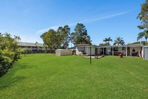 A residential area with a well-maintained lawn, a small outdoor seating area with a fire pit, and a building with a covered patio.