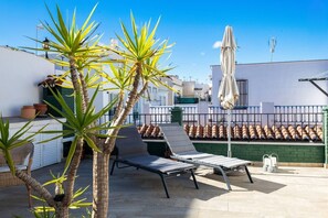 A rooftop terrace with a lounge chair, potted plants, and a large umbrella. - Townhouse, Old Town, Nerja (Nerja)