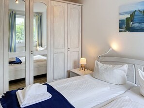 Een hotelkamer met een bed, een nachtkastje, een lamp, een kledingkast en een schilderij aan de muur.