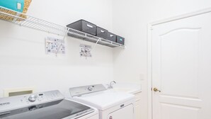 Un cuarto de lavandería con lavadora y secadora Maytag, un lavabo blanco y una puerta blanca.