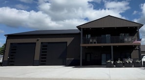 A two-story building with a flat roof, large garage doors, and a balcony with an American flag.