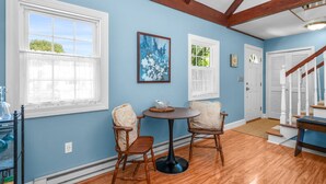 A room with two wooden chairs, a small round table, and a painting on the wall. - Cape Cod Escape – 1 Mile to Beach, A/C & Grill (Centerville)