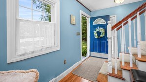 A hallway with a blue door, white-framed windows, and a wooden staircase. - Cape Cod Escape – 1 Mile to Beach, A/C & Grill (Centerville)