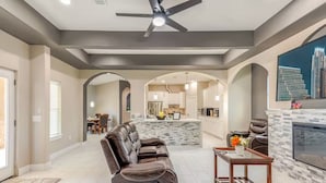 A spacious living room with a leather sofa, a fireplace, and a dining area in the background.