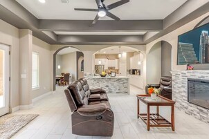 Un salón amplio con sofá de cuero, chimenea y zona de comedor al fondo.