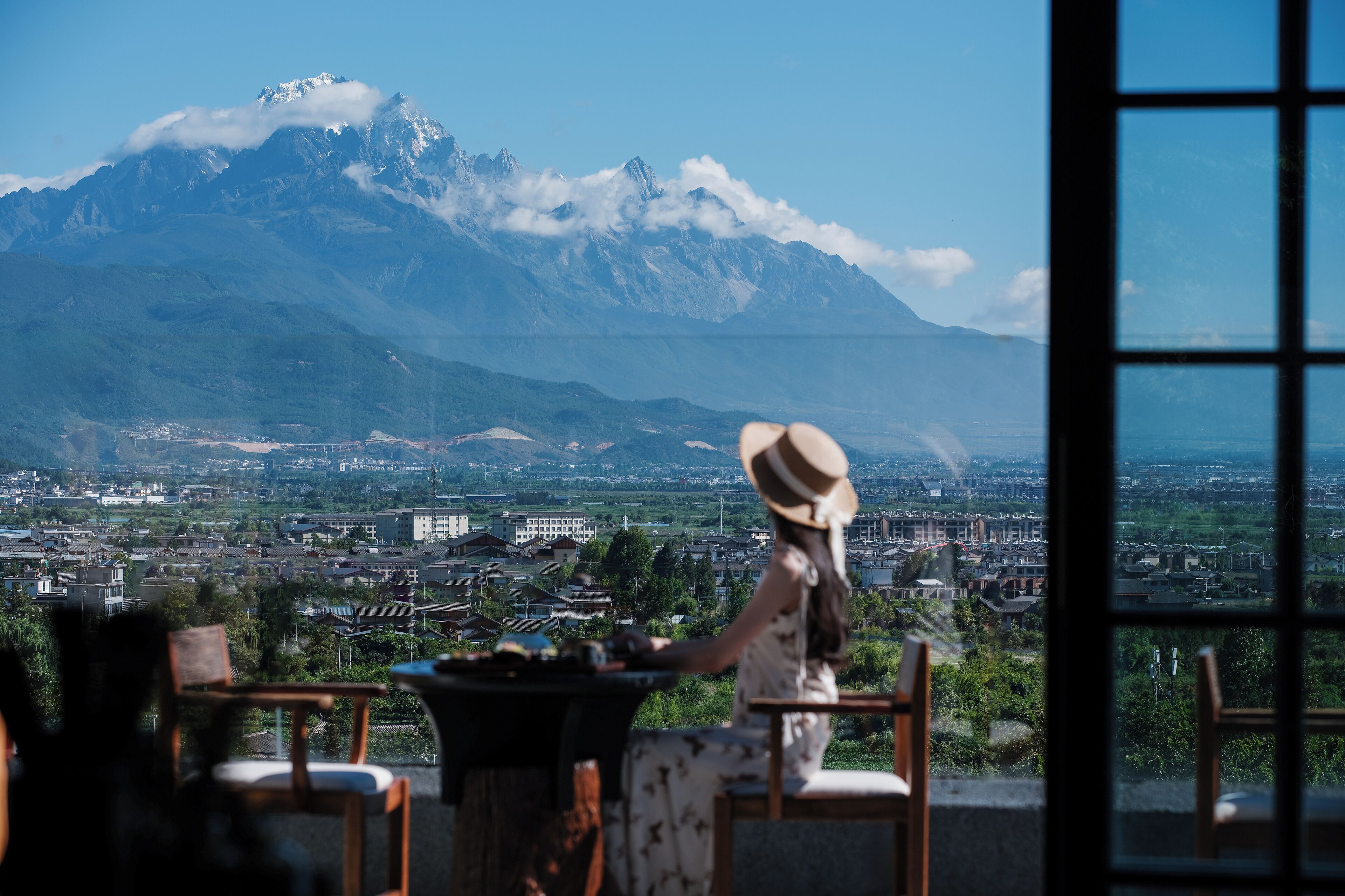 Una persona sentada a una mesa con vistas a una montaña y un paisaje urbano.