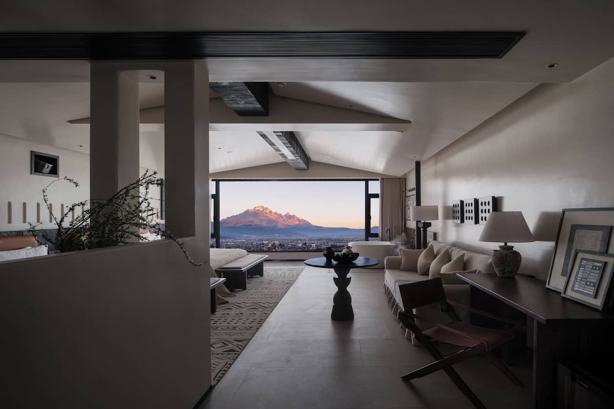 Una sala de estar moderna con vistas a la montaña, un sofá, una mesa de centro y un comedor.