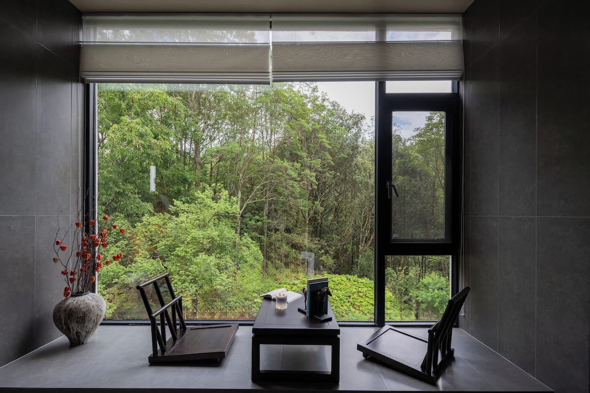 Una habitación moderna con un ventanal grande, una mesita y una silla.
