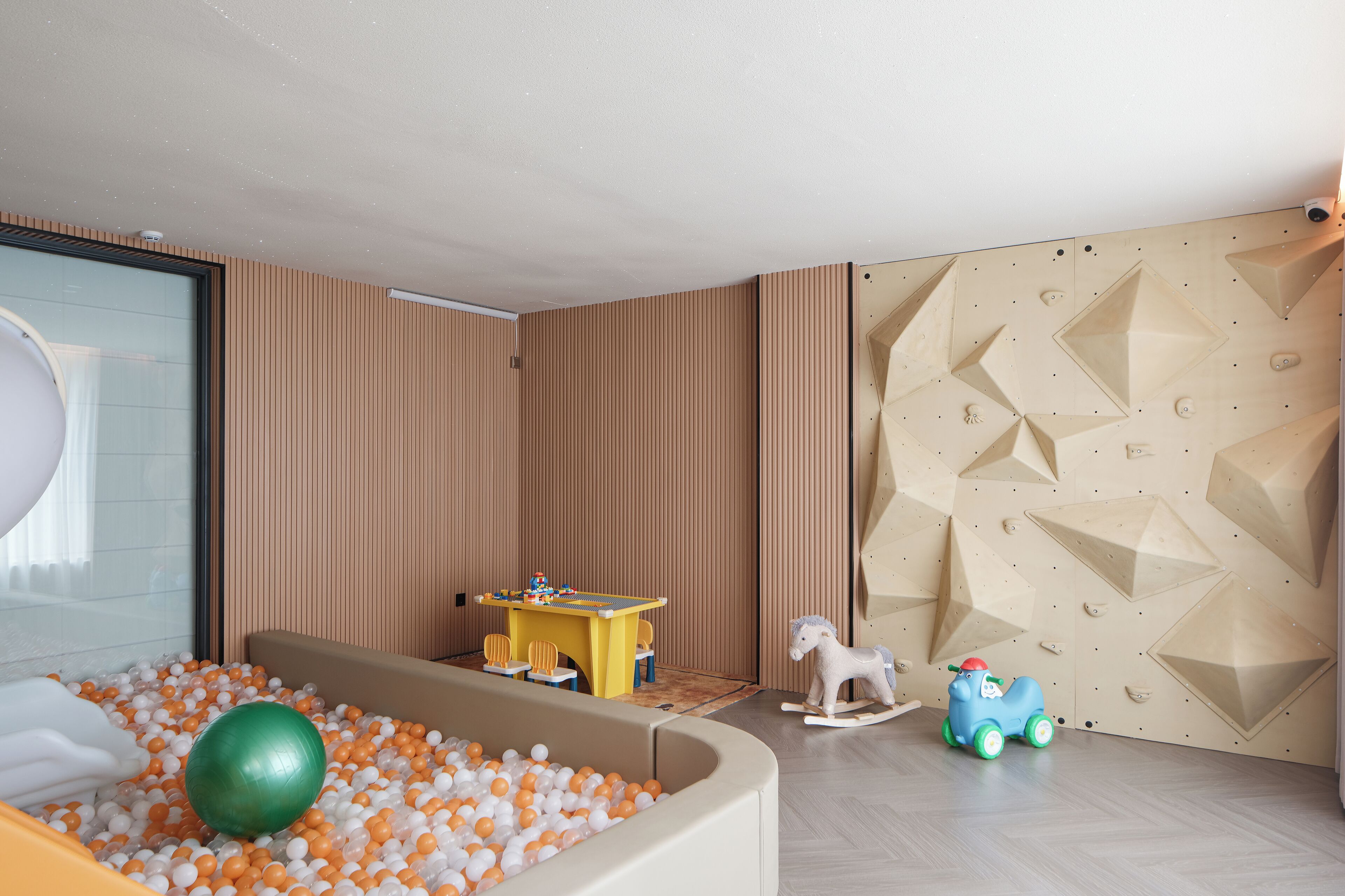 A play area with a ball pit, a small table with chairs, and a climbing wall.