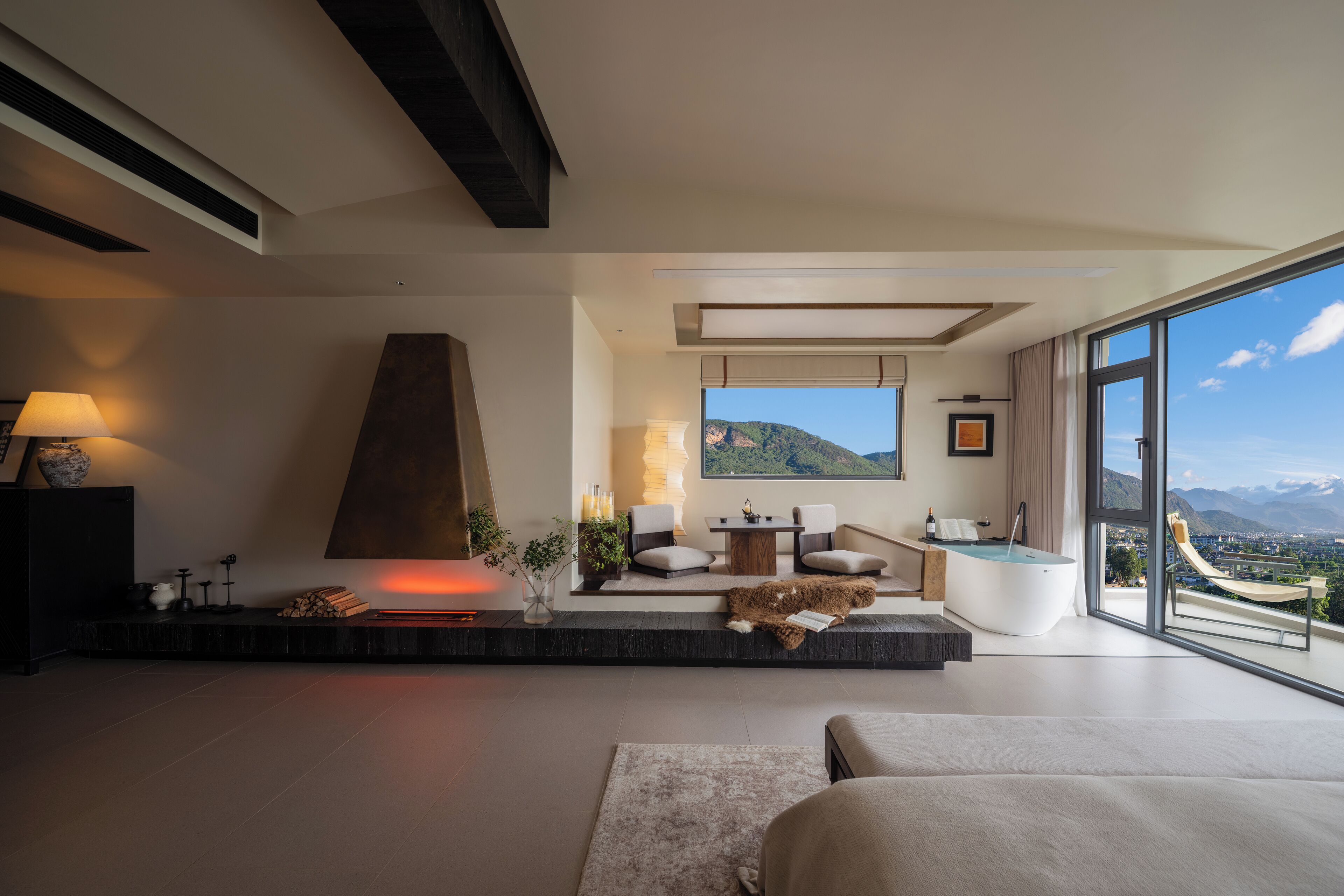Una sala de estar moderna con chimenea, un ventanal con vistas a la montaña y un rincón de descanso acogedor.