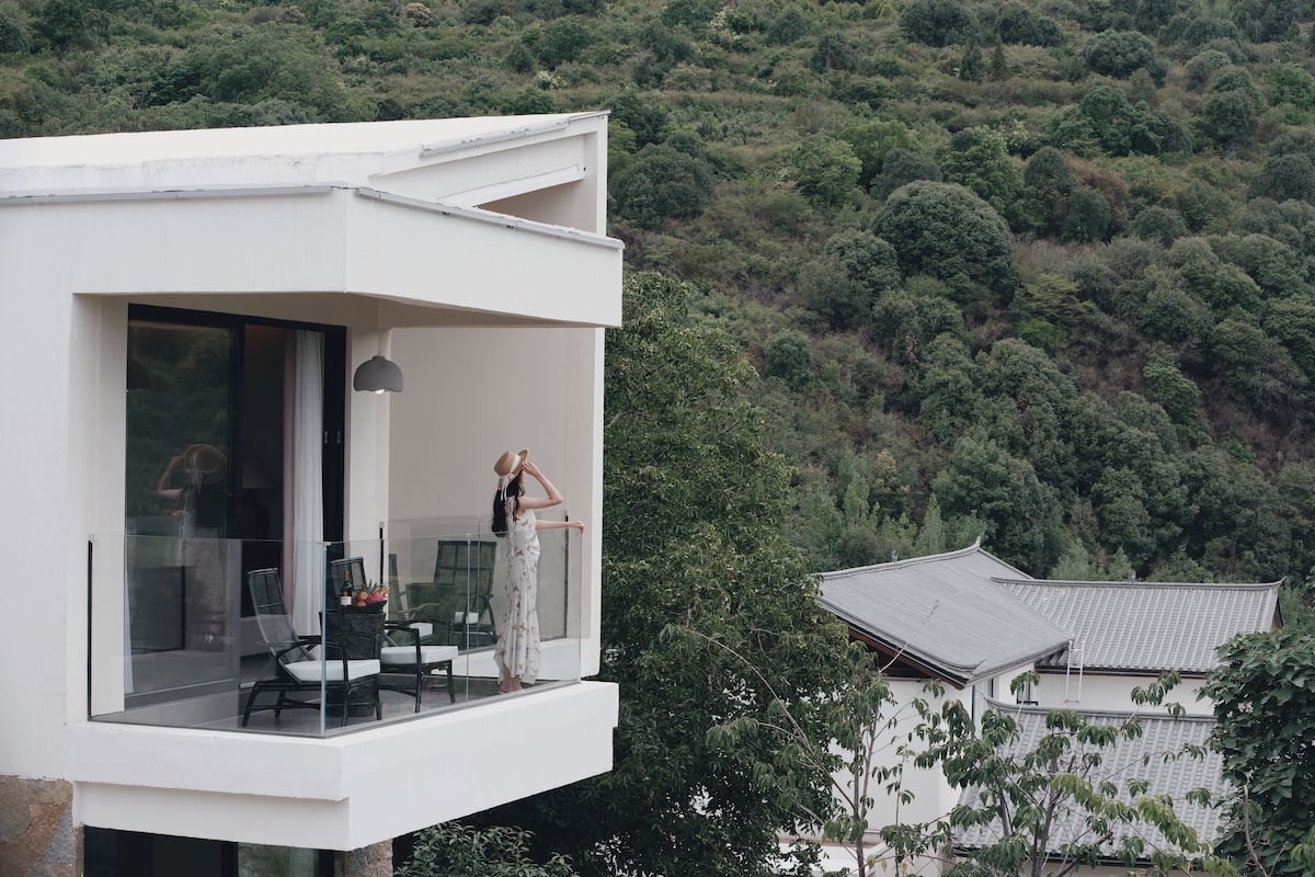 Una casa moderna con un balcón con vista a una ladera boscosa.