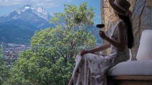 A room with a view of a mountain range, a tree, and a person sitting by a window. - Xiangwang SOOOAN Luxury Resort Hotel (Lijiang)