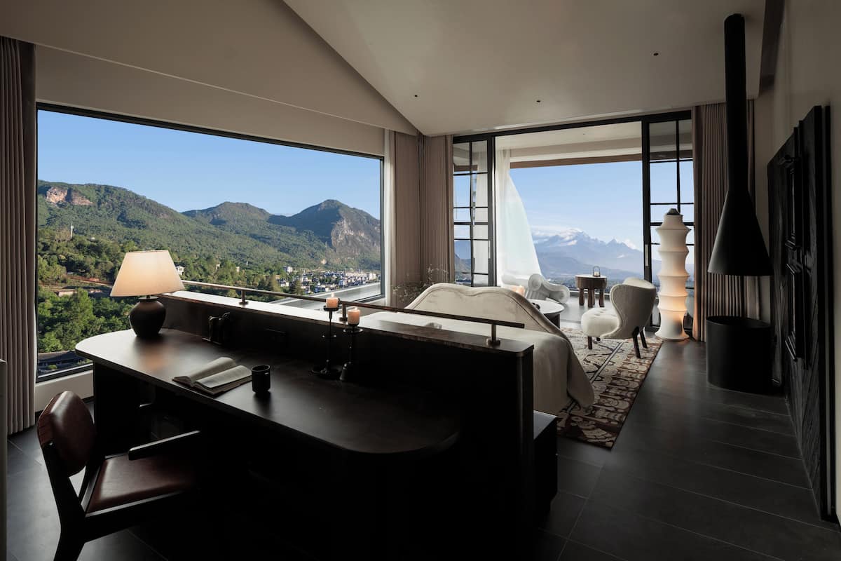 Habitación de hotel moderna con una cama grande, un escritorio y vistas a las montañas.