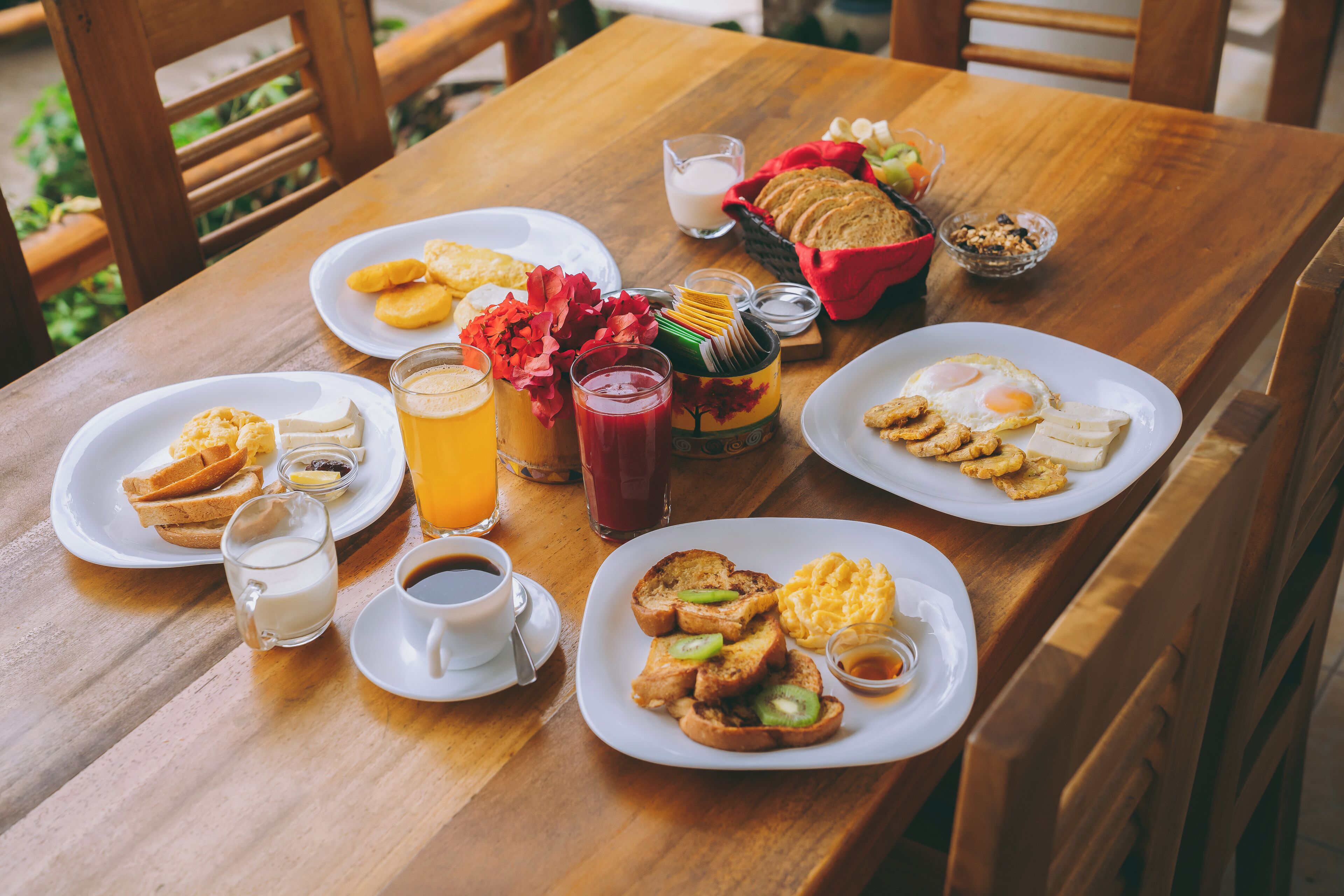 A wooden table with breakfast items including toast, eggs, and beverages.