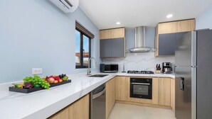 A modern kitchen with a white countertop, stainless steel appliances, and wooden cabinets.