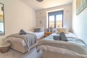 A bedroom with two beds, a window, a nightstand, and a wall-mounted shelf. - Rural Farm Cottage | Outside Space | 2bds & 2baths (Stelling Minnis)
