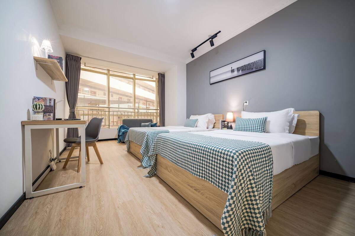A hotel room with a large bed, a desk, a chair, and a window with a view.