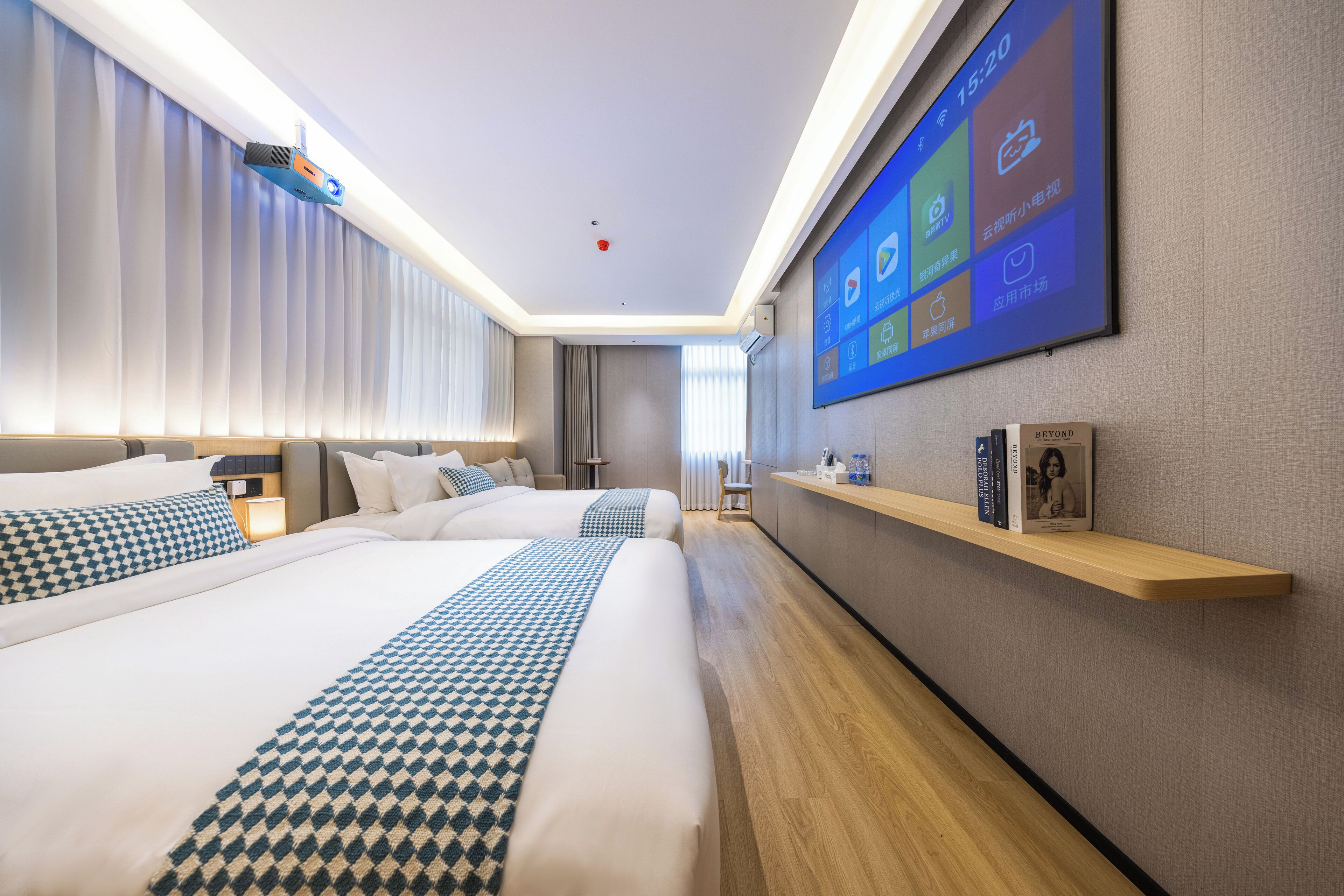 Habitación de hotel moderna con una cama grande, mesitas de noche, un televisor de pantalla plana y una estantería de madera con libros.
