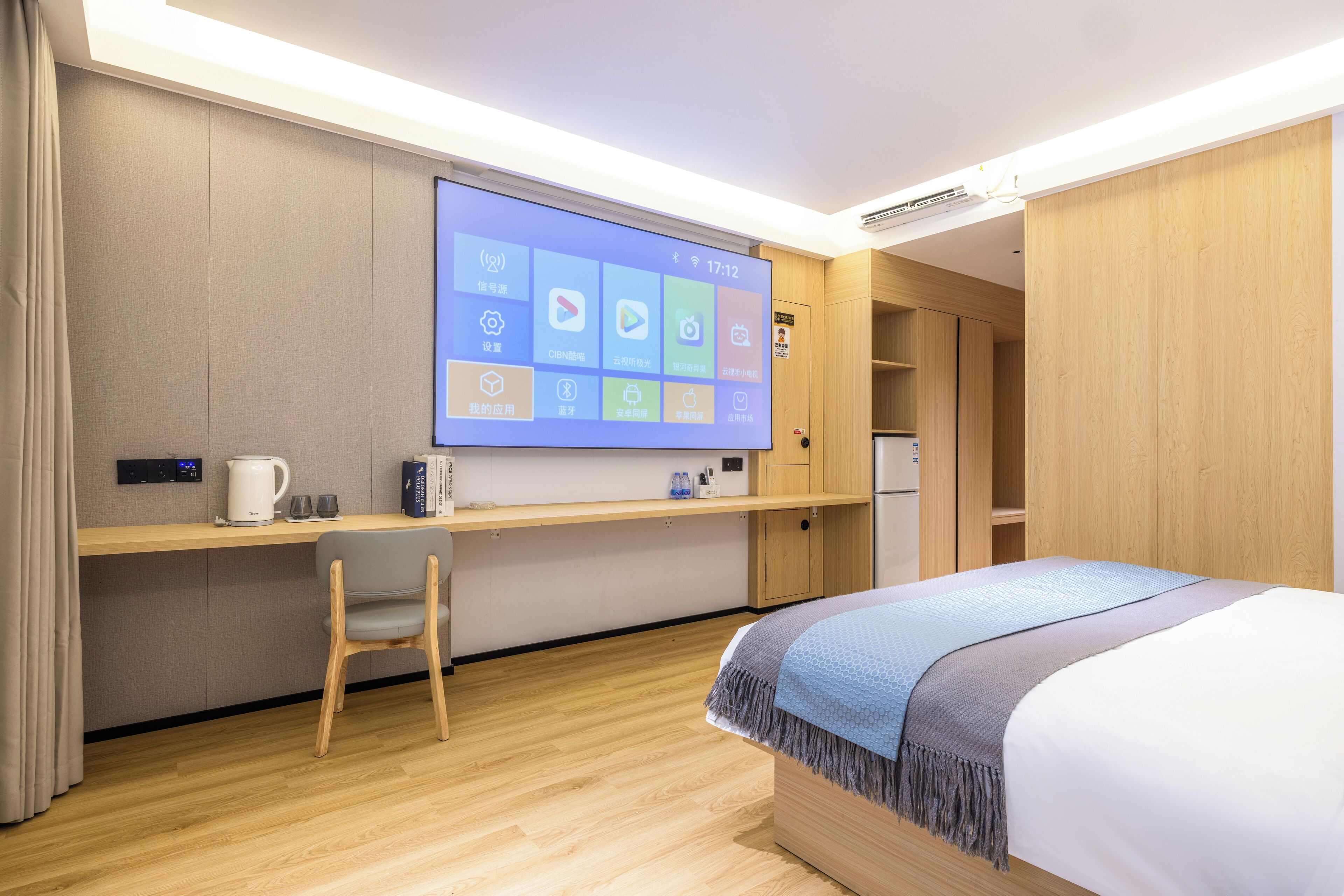 Une chambre d’hôtel équipée d’un lit, d’un bureau, d’une chaise, d’un écran de télévision et d’armoires en bois.