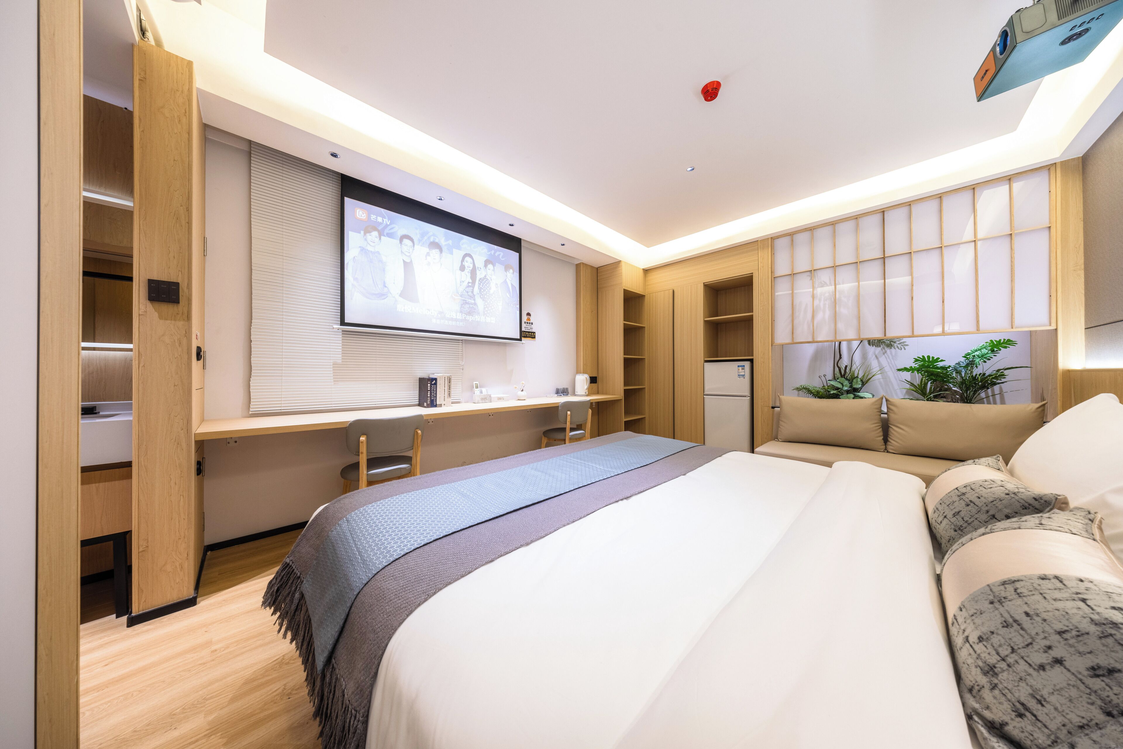 Une chambre d’hôtel moderne équipée d’un grand lit, d’un bureau avec un ordinateur, d’une télévision et d’une armoire.