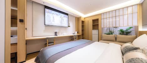Une chambre d’hôtel moderne équipée d’un grand lit, d’un bureau avec un ordinateur, d’une télévision et d’une armoire.