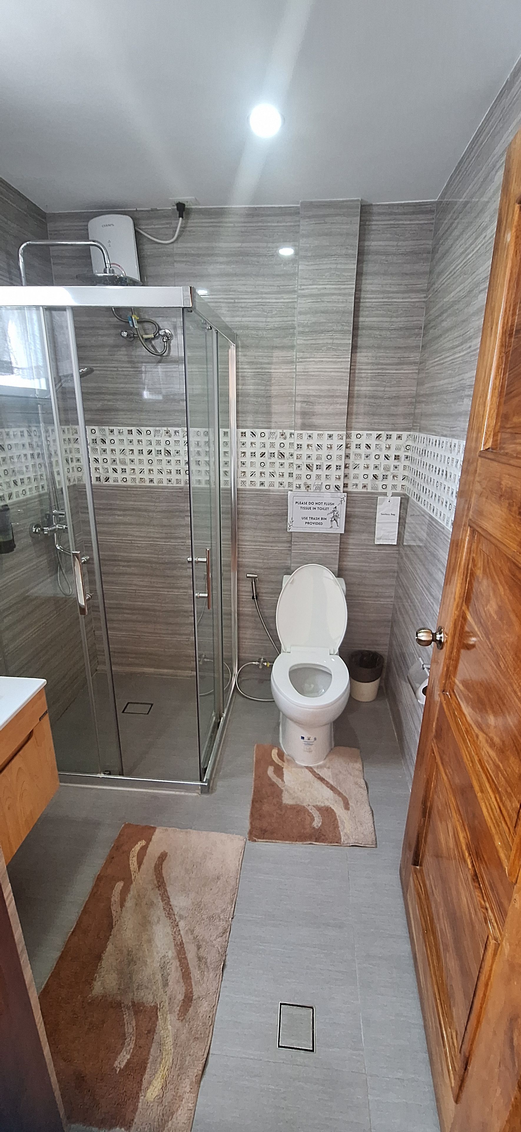 A bathroom with a glass shower enclosure, a toilet, and a sink.