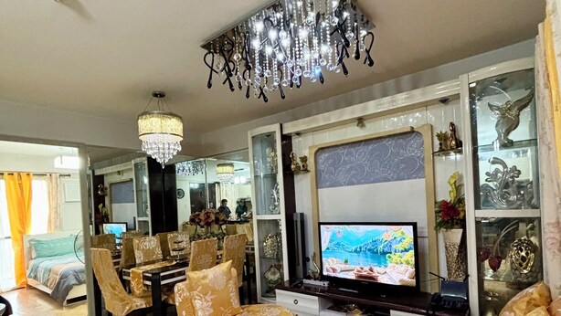 A living room with a television, a chandelier, and floral-patterned sofas.