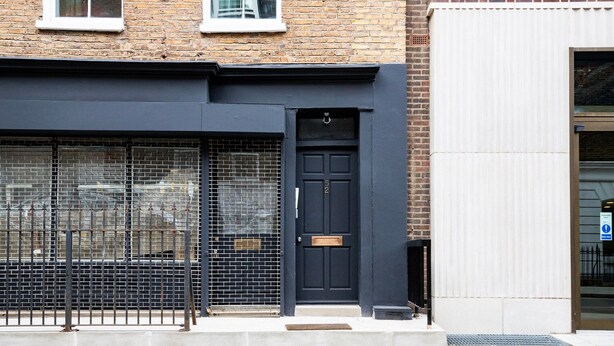 A building with a black door, a metal gate, and a brick facade. - Blueground | Fitzrovia, view, nr British Museum (London)