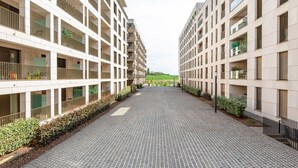 A modern building with a central courtyard, featuring a brick pathway and greenery along the sides.