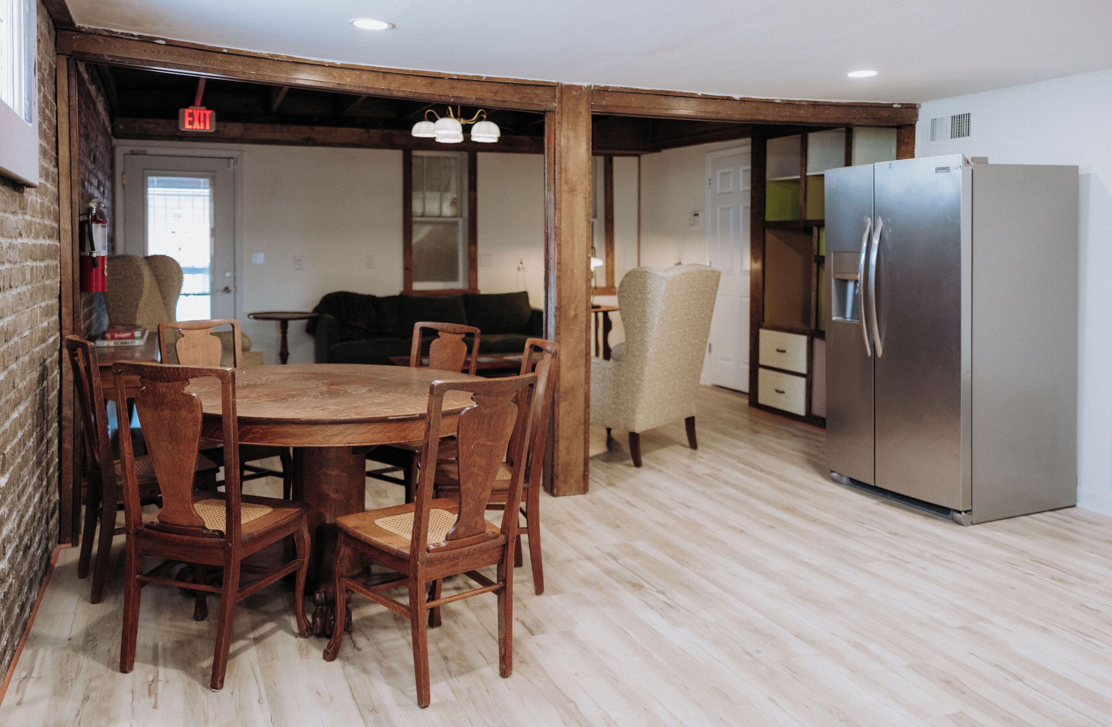 A dining area with a wooden table and chairs, a sofa, and a refrigerator.