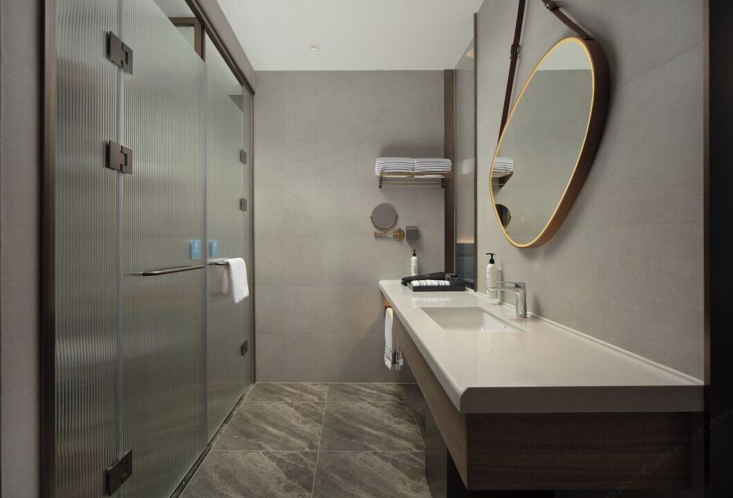 A modern bathroom with a glass shower, a vanity with a mirror, and a towel rack.