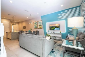 A modern living room with a grey sofa, a TV, and a lamp. - Near Disney Premium Location Summervile Resort (Kissimmee)