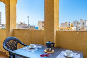 Een balkon met een tafel gedekt voor twee personen, een koffiezetapparaat en twee glazen.