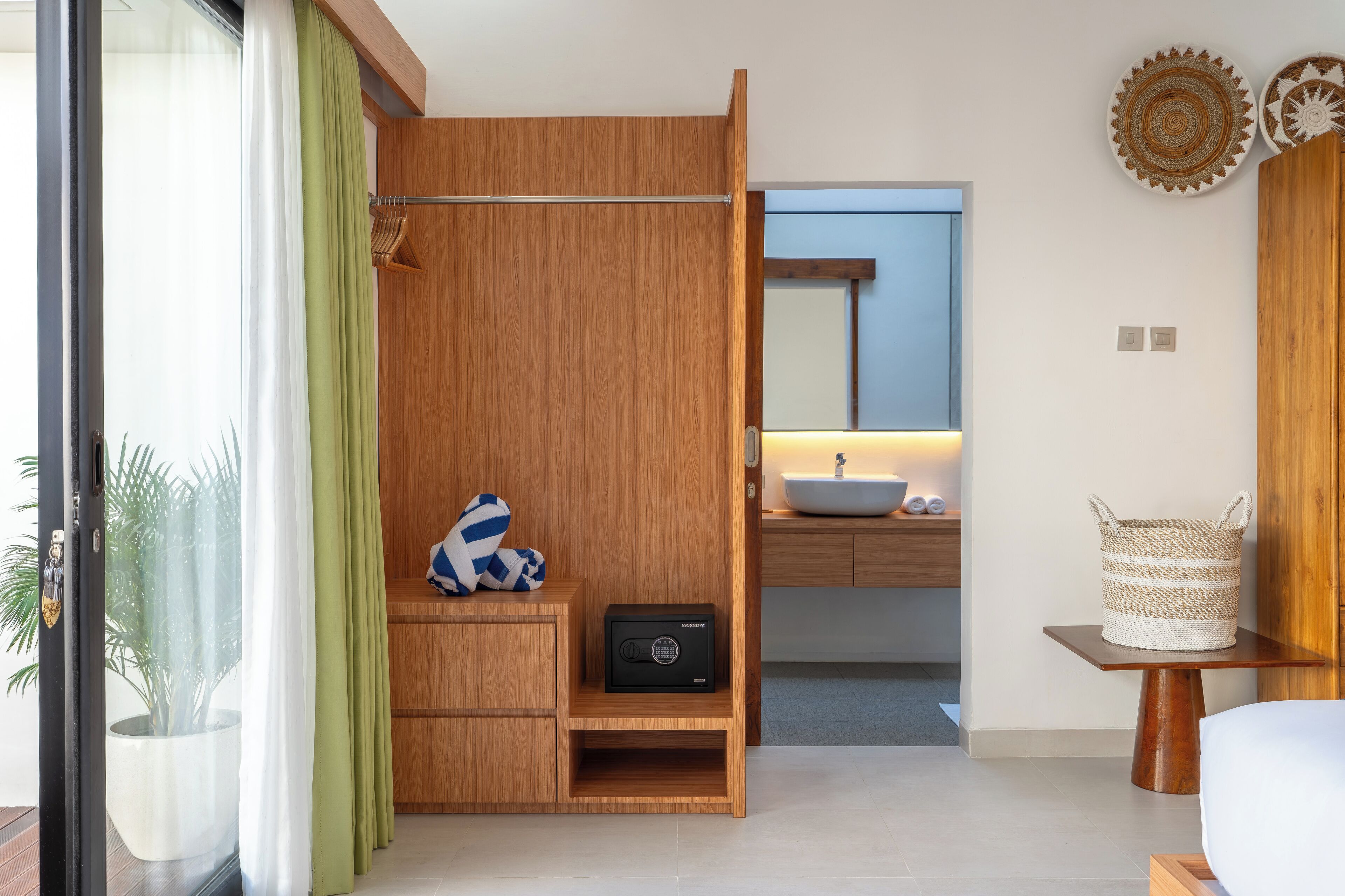 Une salle de bain moderne avec un meuble-lavabo en bois, un évier et un miroir. On y trouve également un porte-serviettes et un panier sur le meuble-lavabo.