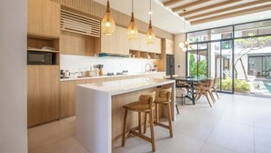 Een moderne keuken met houten kastjes, een centraal kookeiland met barkrukken en hanglampen.