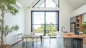 Una cocina moderna con un ventanal grande, un comedor con sillas y una planta en maceta.