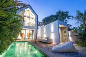 Ein modernes, zweistöckiges Haus mit Pool, Außenbereich mit Sitzgelegenheit und separater Dusche.